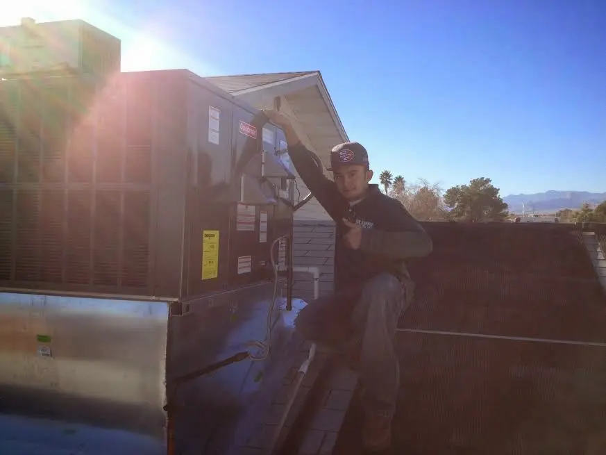 HVAC technician performing Air Duct Cleaning on a rooftop unit in Kyle